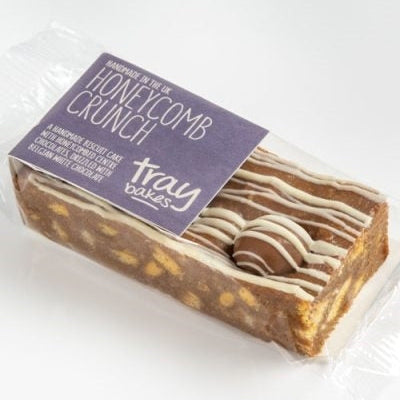 Packaged honeycomb crunch biscuit cake with visible white chocolate drizzle, branded as TRAYBAKES.