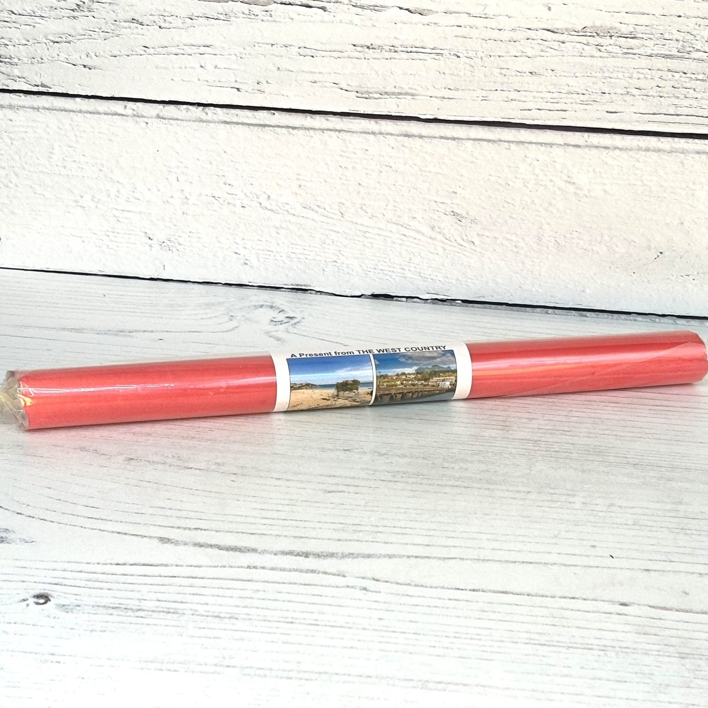 A roll of mint rock candy with red packaging, displaying a label that includes text and a scenic image, placed on a wooden surface.