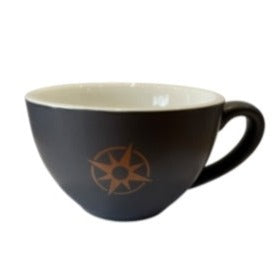 A flat white cup with a dark brown color and a brown compass-like design on the side.