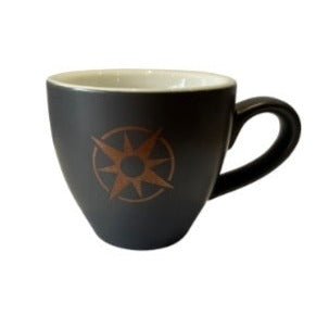 A black ceramic espresso cup with a brown compass-like design on the side, without any visible branding.