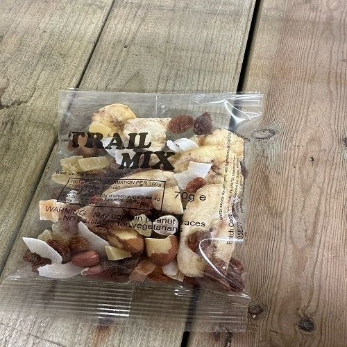 Packaged trail mix snacks on a wooden surface. The package indicates a weight of 70g and includes a variety of dried fruits and nuts.