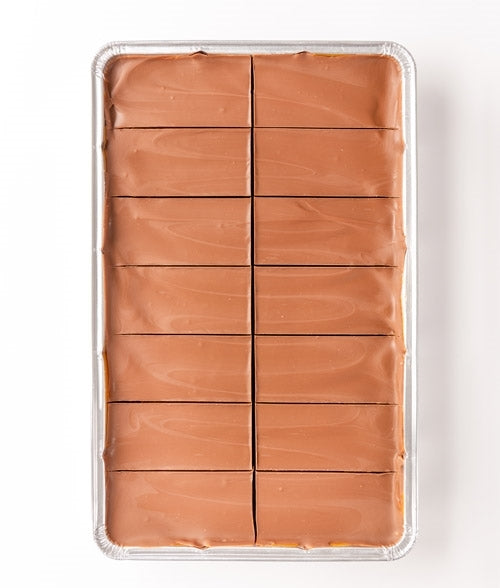 A tray of caramel shortcake slices covered with chocolate, arranged in rows.