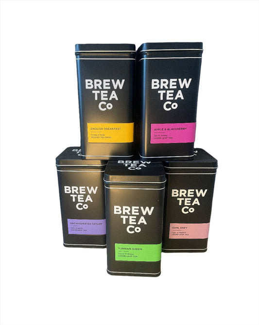 Five black storage tins of BREW TEA CO. with different colored labels indicating various tea flavors.