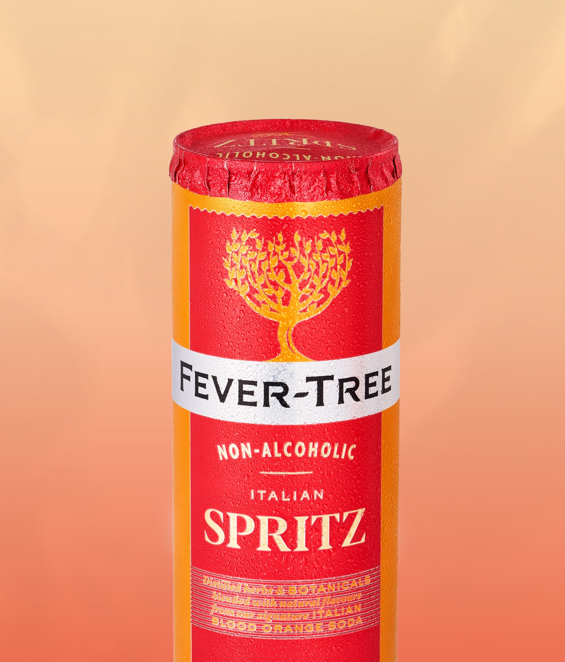 A cylindrical canister of Fever-Tree Non-Alcoholic Italian Spritz non-alcoholic beverage, featuring a red and orange label with a gold tree logo and a white band with black text, set against a warm peach gradient background.