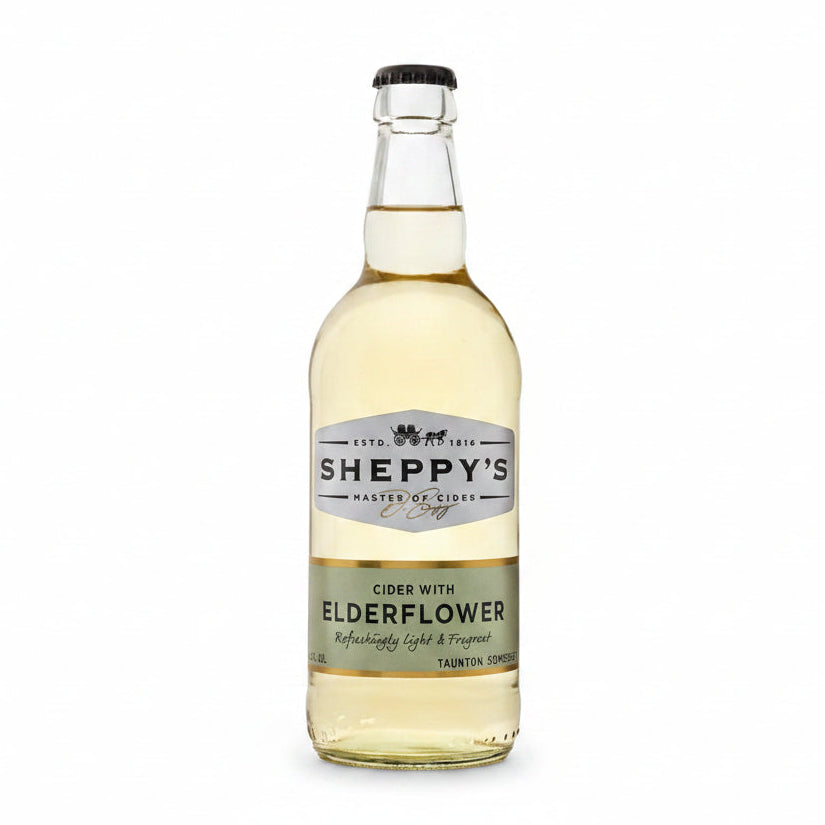 A bottle of Sheppy's Cider with Elderflower, featuring a clear glass bottle filled with pale golden liquid, a black cap, and a white and gold label.