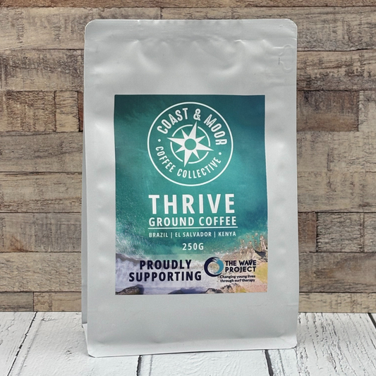 Coast & Moor Coffee Collective Thrive ground coffee package on a wooden background
