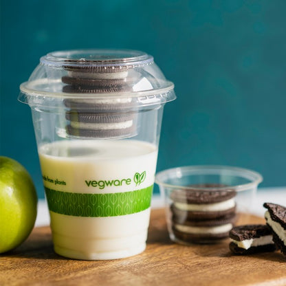 Vegware container with milk and cookies on a wooden surface.
