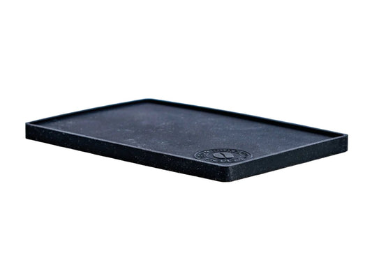 A black rectangular trivet mat used for placing under hot dishes to protect surfaces.