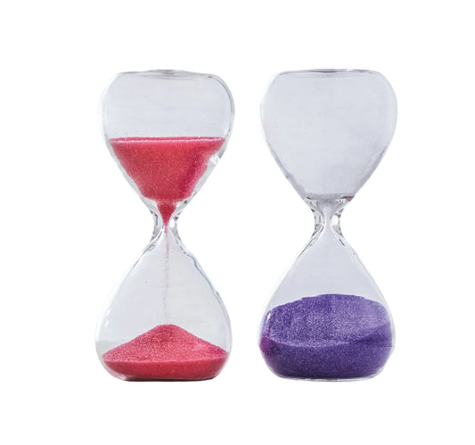 Two clear glass tea timers with pink and purple sand, one with pink sand and the other with purple sand, on a white background.
